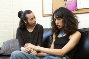 A genderqueer person comforting a transgender woman on a therapists couch - co-regulation during meetings - Sociocracy For All