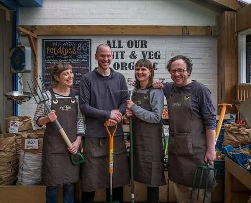 Grocery cooperative members holding farming tools.