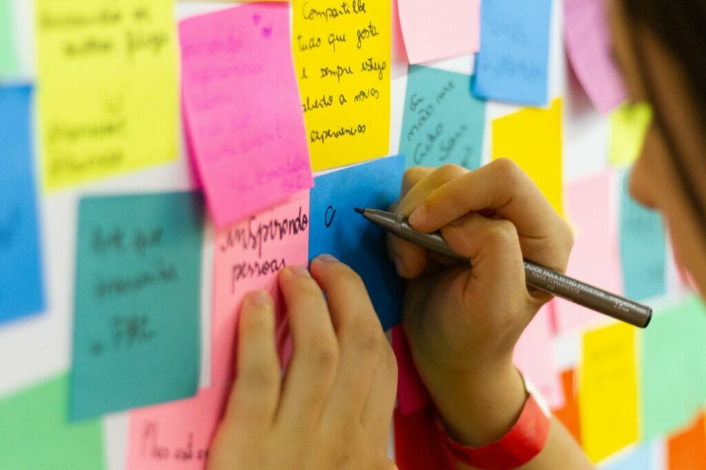 Imagen de una persona escribiendo una retroalimentación en un post-it para quizá una evaluación de desempeño