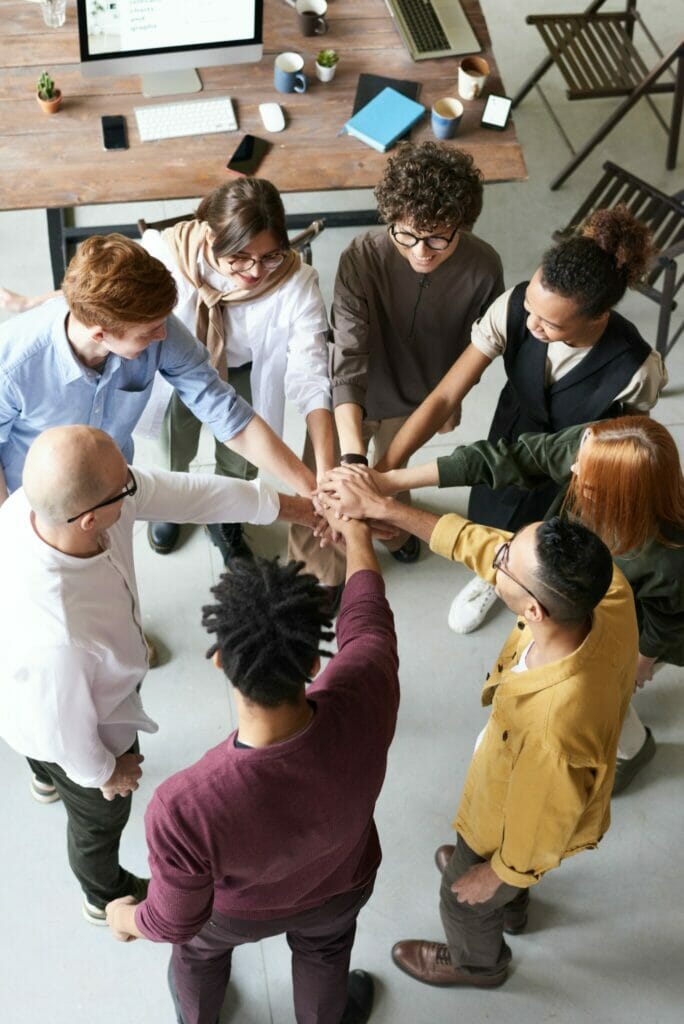 People standing in a circle putting their hands in the middle