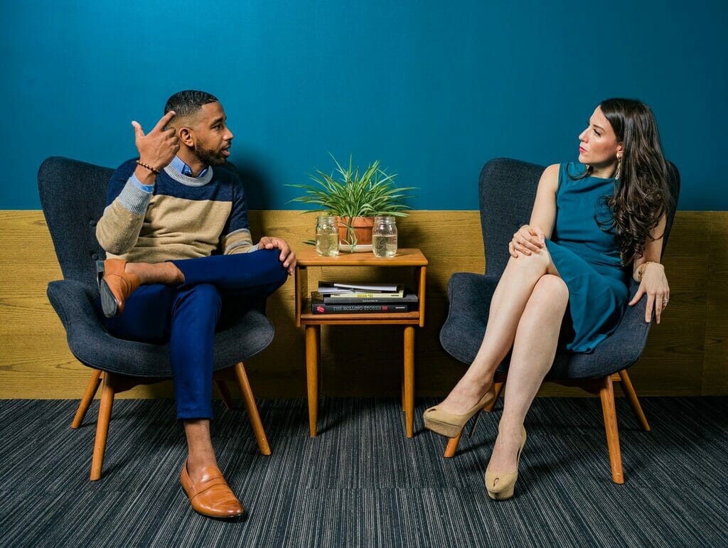 A man and a woman sitting in chairs talking and listening - Sociocracy For All